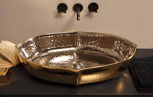 A luxurious golden wash basin with a contemporary design, mounted on a dark-colored vanity cabinet.