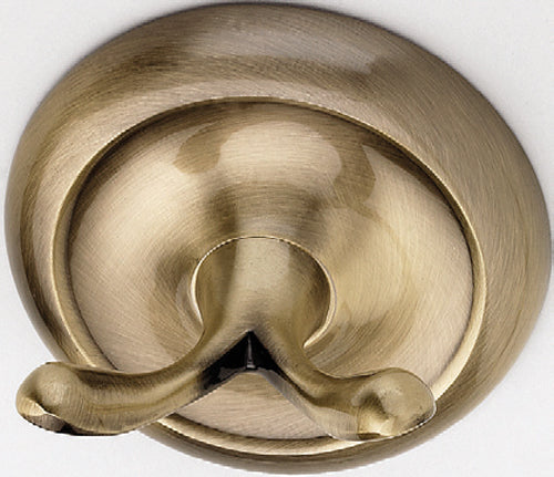 A gold-colored wall hook with a round backplate and two upward facing hooks.