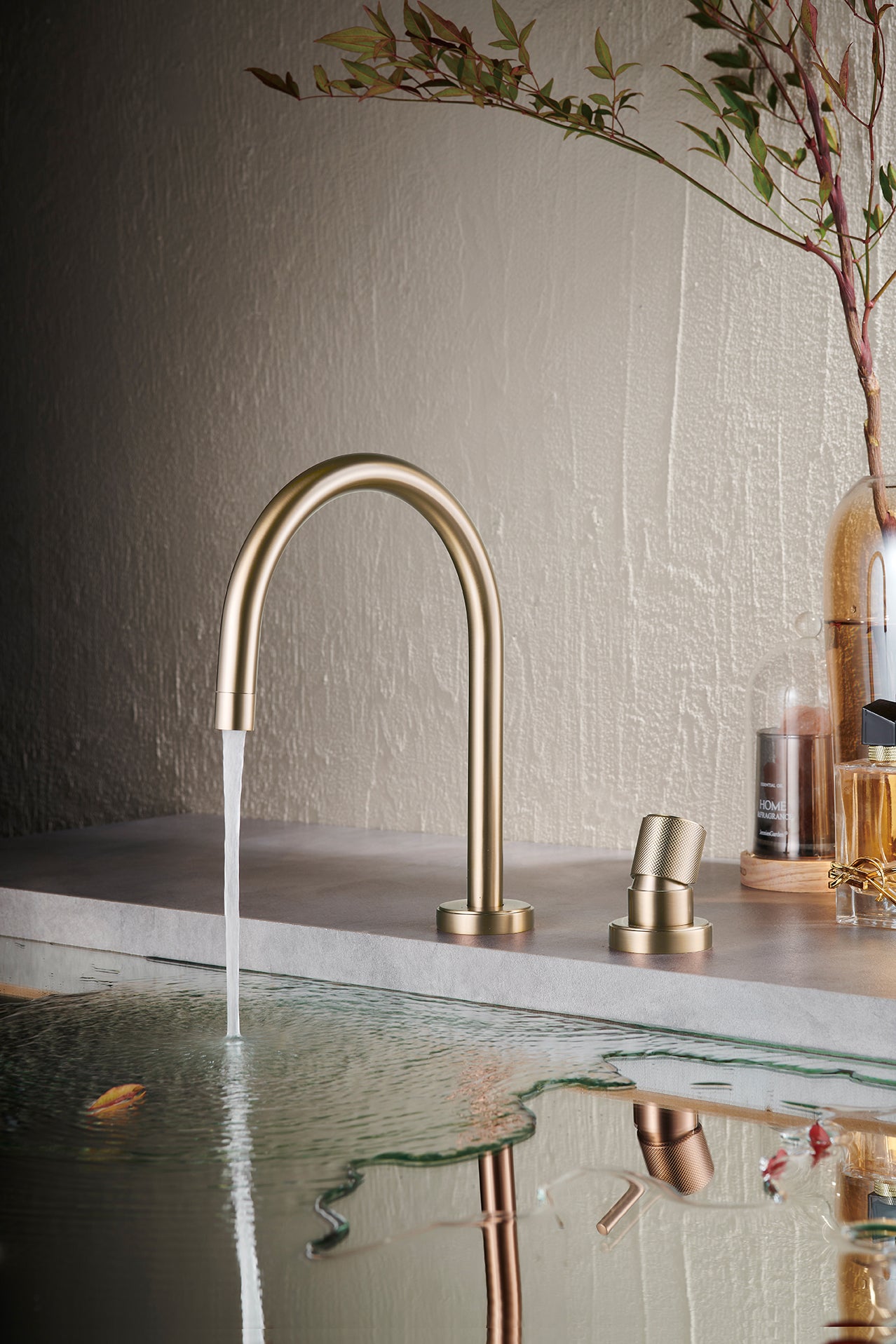 Champagne gold basin mixer faucet with water flowing into a sink against a neutral wall.