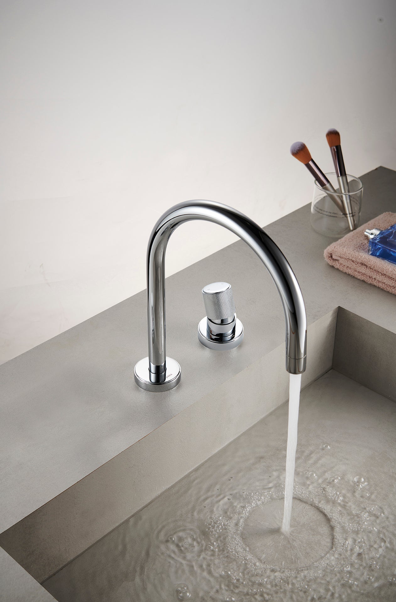 Modern chrome basin mixer faucet with water flowing into a sink