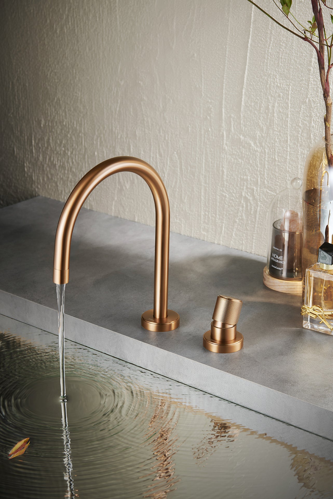 Rose gold basin mixer faucet with water flowing into a sink on a concrete surface.