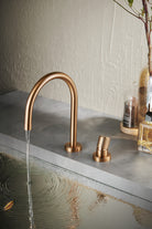 Rose gold basin mixer faucet with water flowing into a sink on a concrete surface.